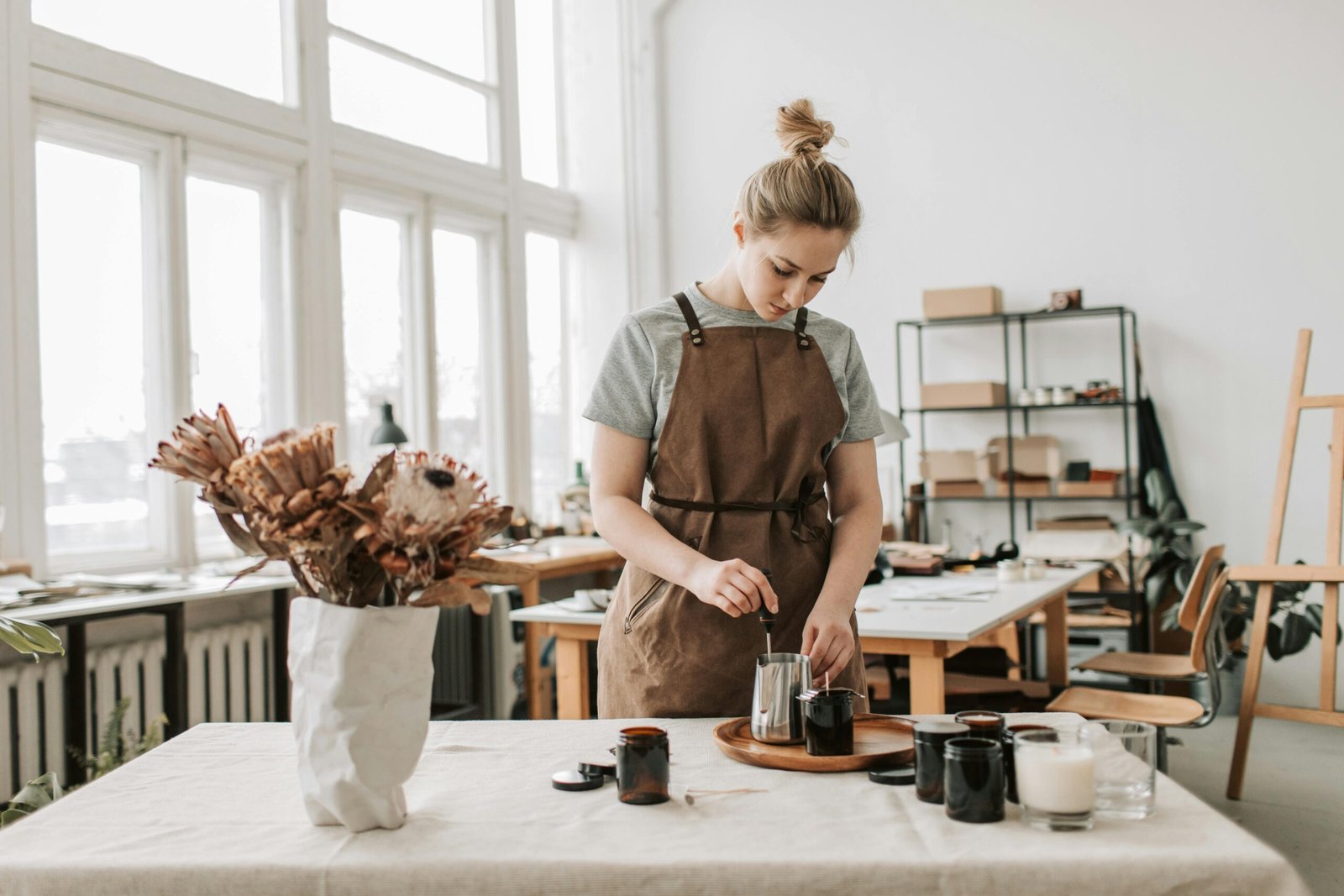 A woman craftsperson creating handmade candles in a bright, airy workshop.